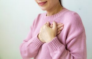 Symbolbild Jin Shin Jyutsu Herzrhythmusstörungen: Frau hält Hände auf ihr Herz
