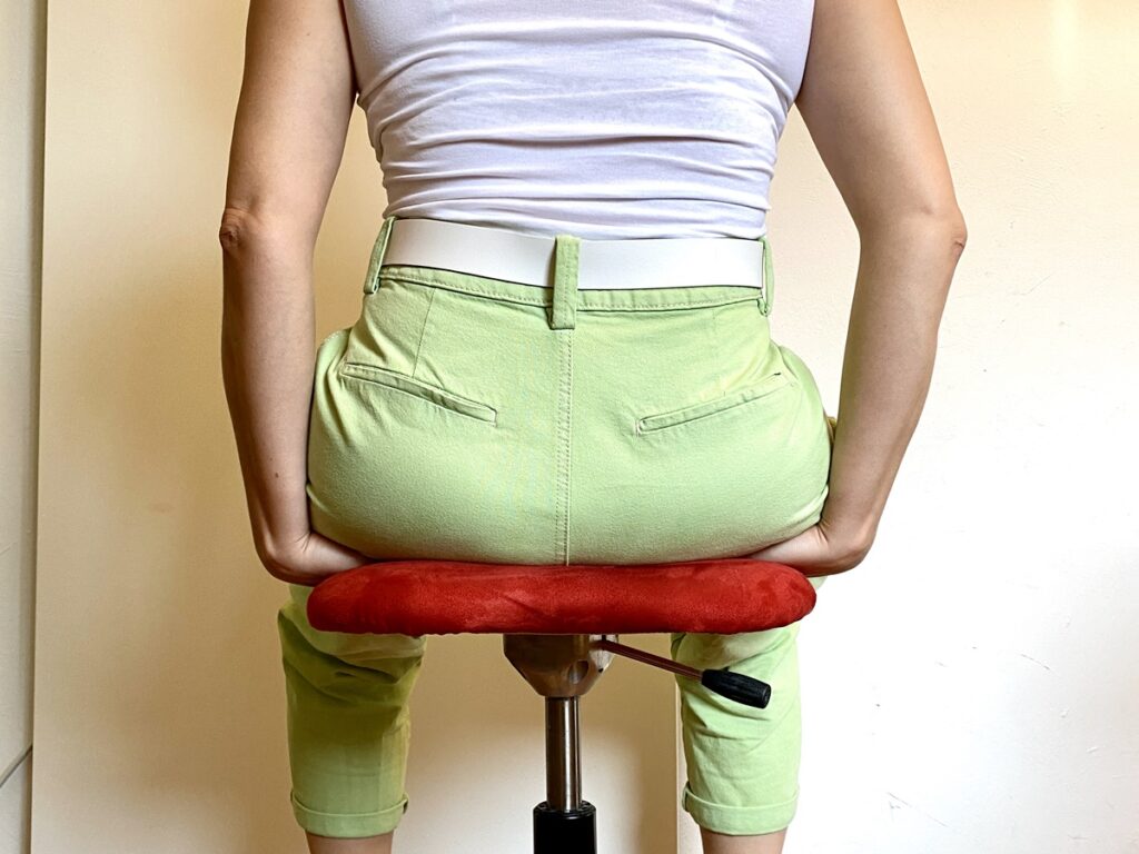 Übung im Jin Shin Jyutsu bei Diabetes: Frau sitzt mit Sitzhöckern auf beiden Handflächen