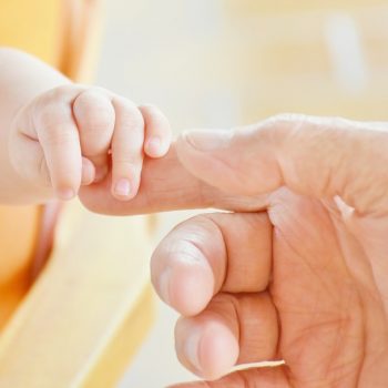 Symbolbild Jin Shin Jyutsu für Kinder: Babyhand berührt erwachsene Hand