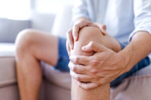Symbolbild Jin Shin Jyutsu Knieschmerzen: Mann hält sich sein schmerzendes Knie