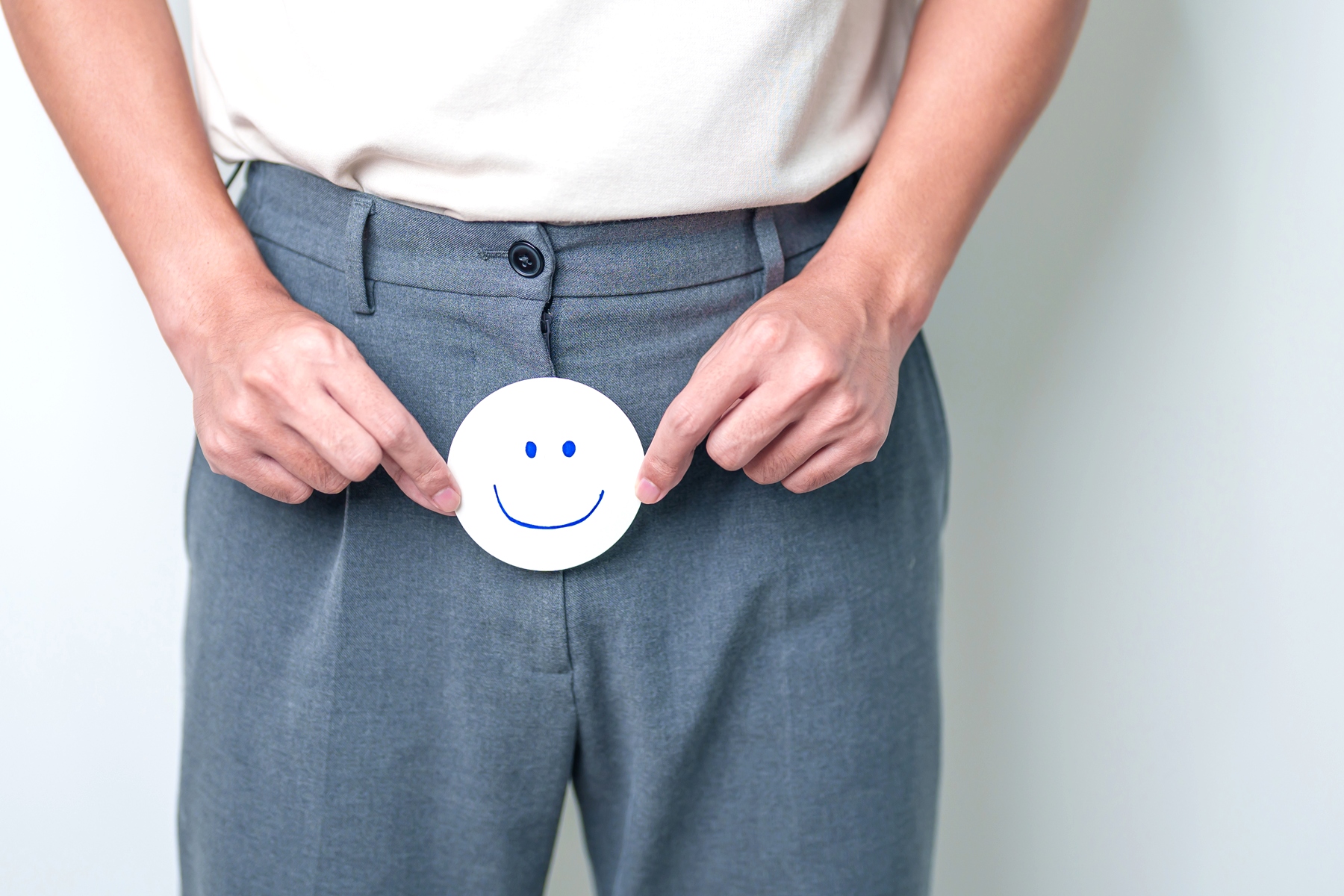 Mann hält lächelnden Emoji vor seine Prostata als Symbolbild für Jin Shin Jyutsu für die Prostata